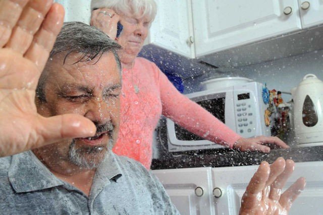 Burst pipe spraying water in a kitchen during a plumbing emergency